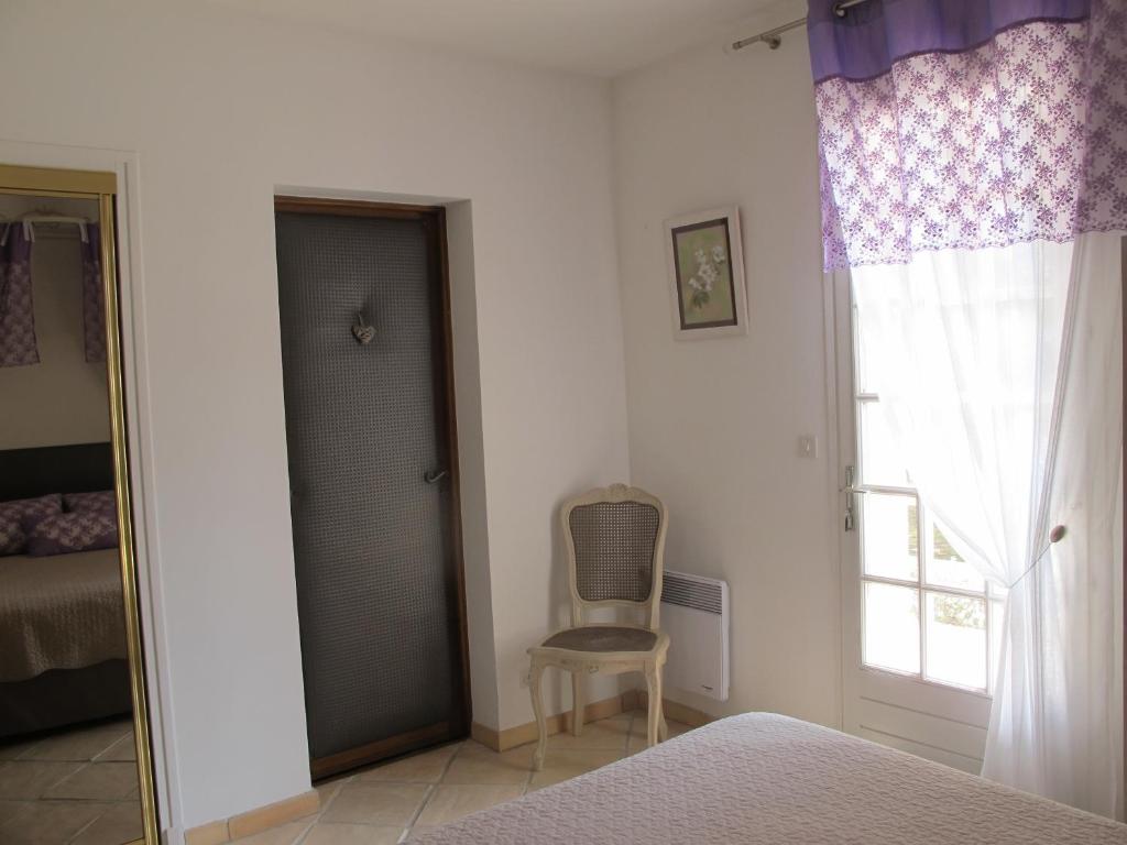 a bedroom with a bed and a chair next to a window at L&#39;Oustau de Bigatié in Lambesc