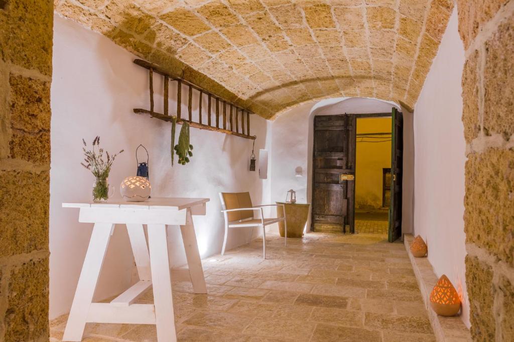 Habitación con mesa blanca y pared de piedra. en Il Cortile dei Nonni, en Morciano di Leuca