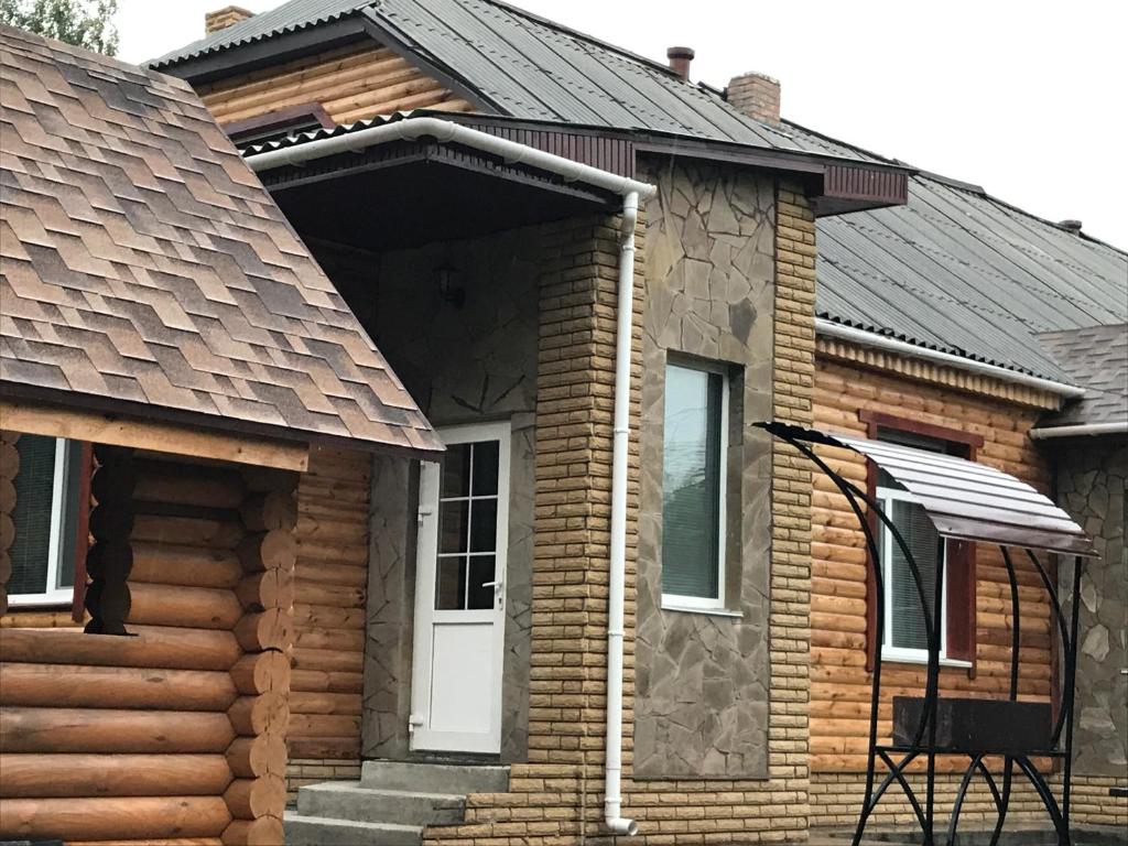 a log house with a white door and a porch at Holiday Home Rayskiy Ugolochek in Kvitki