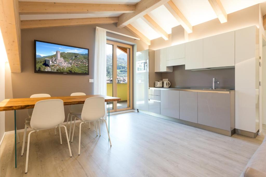 a kitchen with white cabinets and a wooden table and chairs at La Giostra Home Apartments in Drena