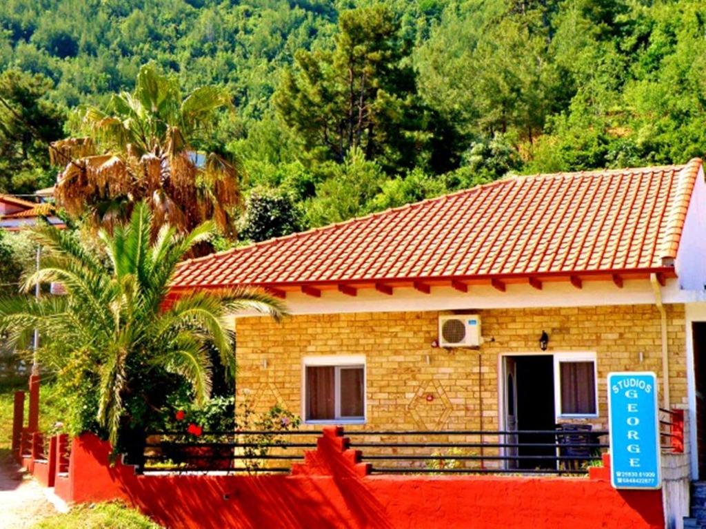 een klein huis met een rood hek ervoor bij George Studios in Skala Potamias