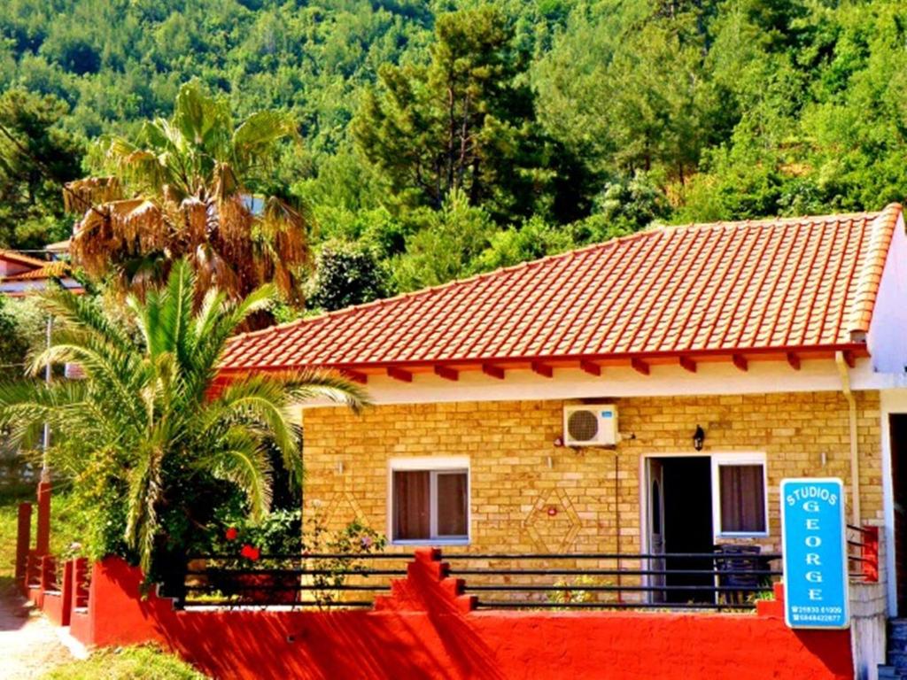 a small house with a red fence in front of it at George Studios in Skala Potamias