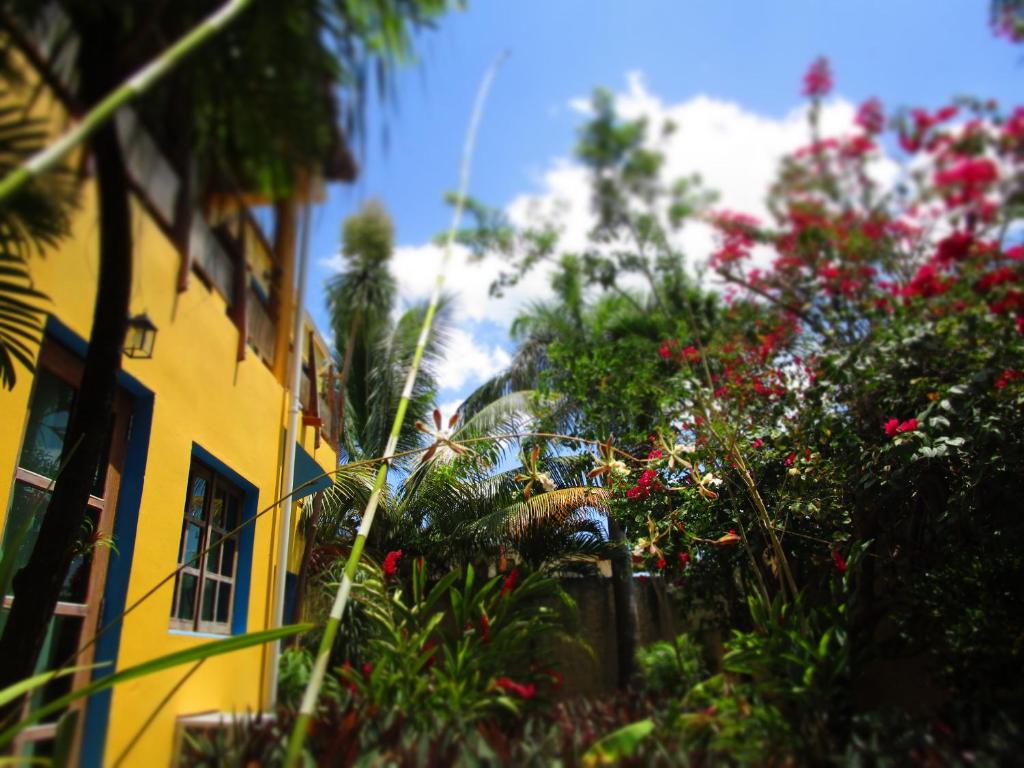 a yellow building with trees and flowers in front of it at Casa Abanico Tulum in Tulum