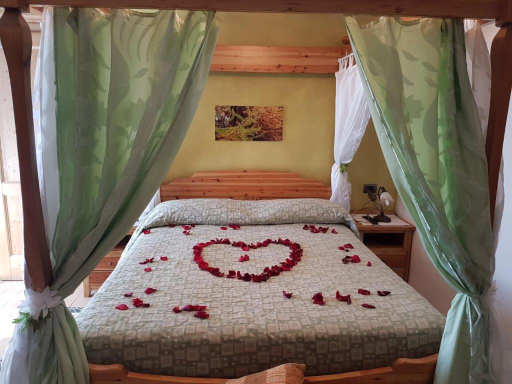 ein Bett mit einem Herz aus Rosen in der Unterkunft Agriturismo Ca' di Racc in Gromo
