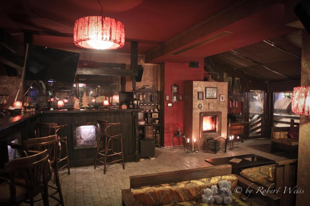 a pub with a bar with a fireplace and chairs at Pensiunea Vlahia Inn in Moieciu de Sus