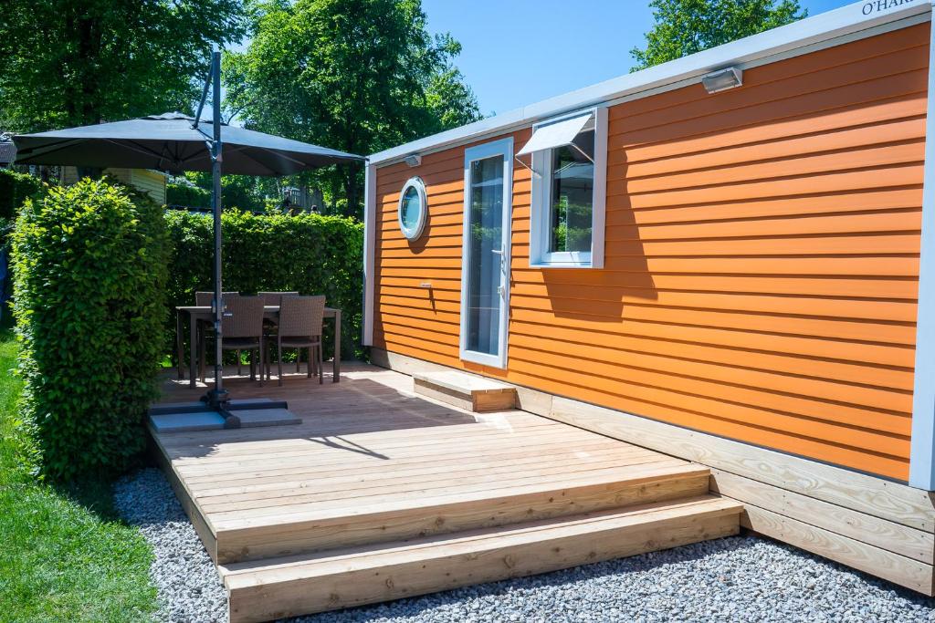 eine Hütte mit einer Holzterrasse und einem Sonnenschirm in der Unterkunft Am See 90 in Seekirchen am Wallersee