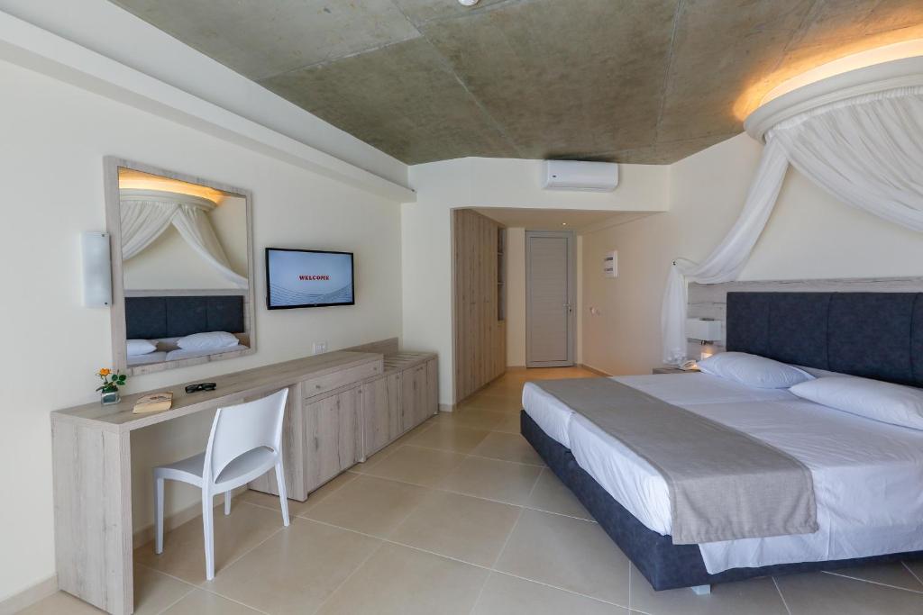 a bedroom with a bed and a desk and a television at Rodos Star Hotel in Afantou