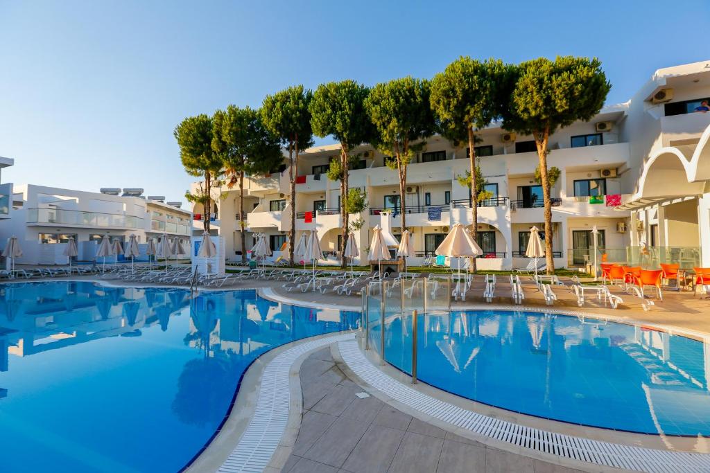 ein Pool in einem Hotel mit Stühlen und Sonnenschirmen in der Unterkunft Rodos Star Hotel in Afandou