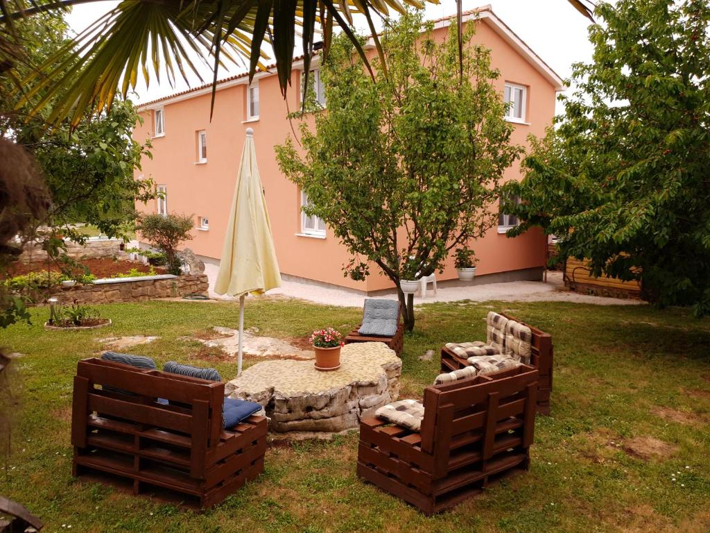 un patio con 2 sillas, una mesa y una sombrilla en Apartmani Marina & Ana, en Poreč