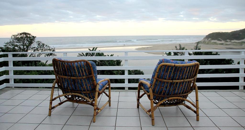 two chairs sitting on a balcony looking at the ocean at Gill's Beach House in Chintsa