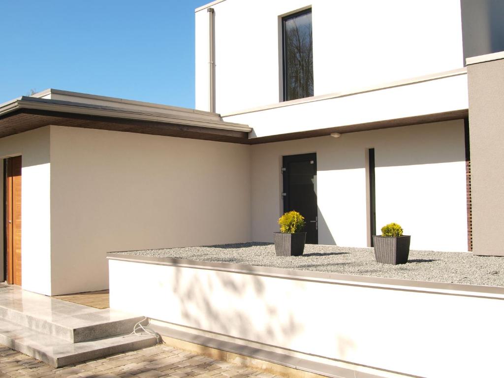 a white house with two potted plants on it at Rinkus in Saulkrasti