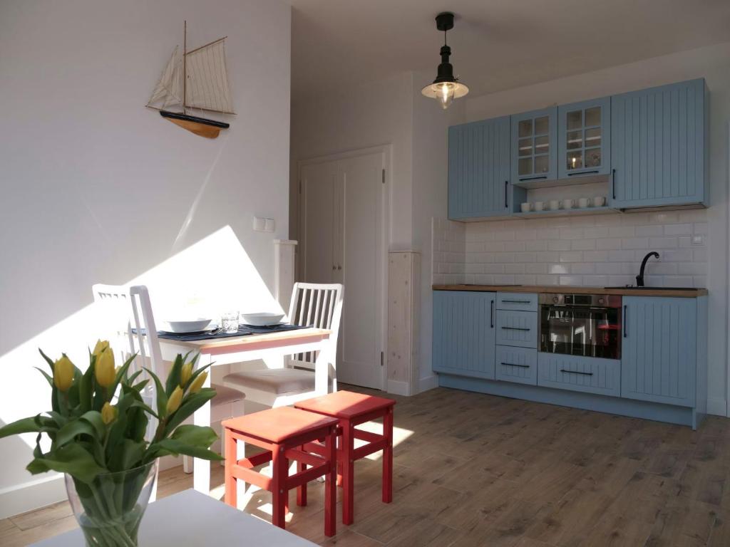uma cozinha com armários azuis e uma mesa e cadeiras em Apartament Biały Żagiel em Rowy