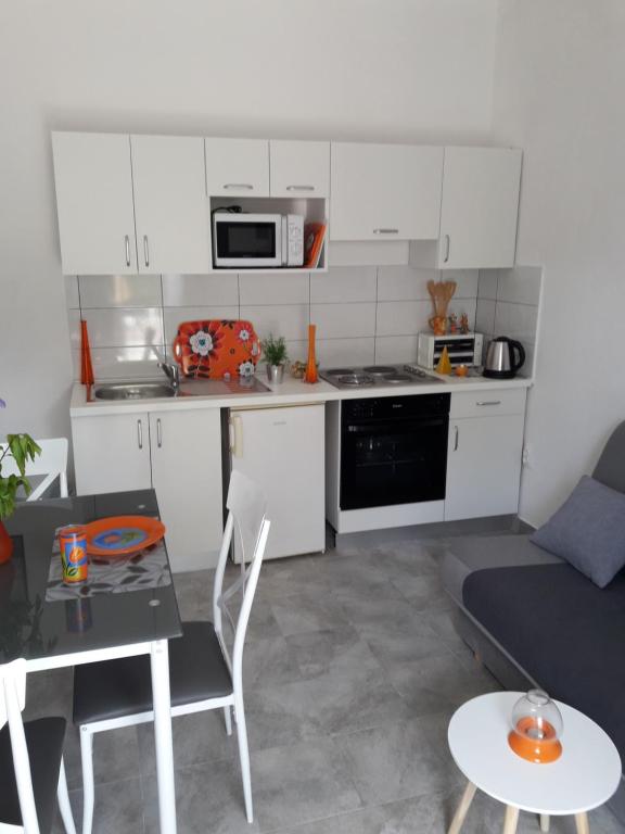 eine Küche mit weißen Schränken, einem Tisch und einer Couch in der Unterkunft Pauli in Kaštela