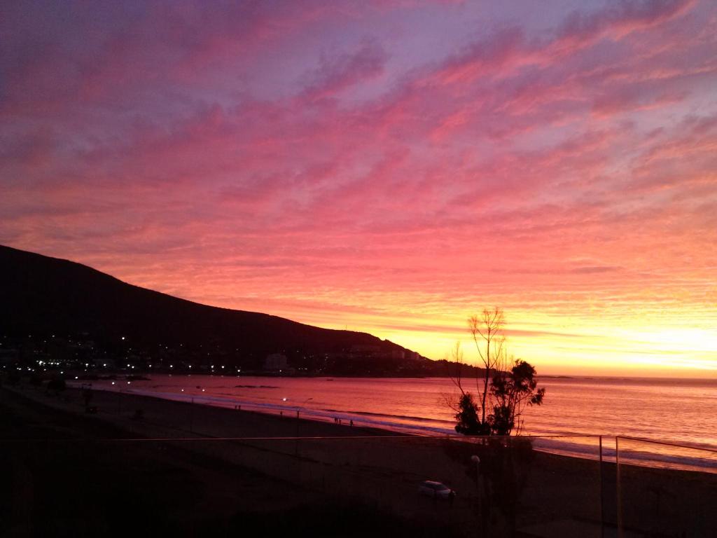 una puesta de sol sobre un cuerpo de agua con una montaña en Papudo Laguna Acceso Playa, en Papudo