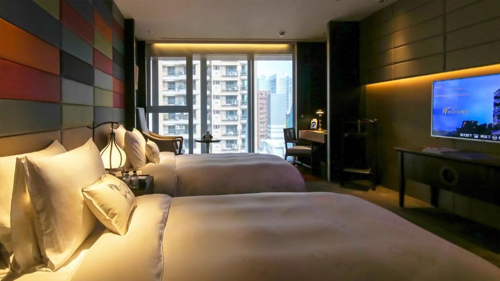a hotel room with two beds and a flat screen tv at H2O HOTEL in Kaohsiung