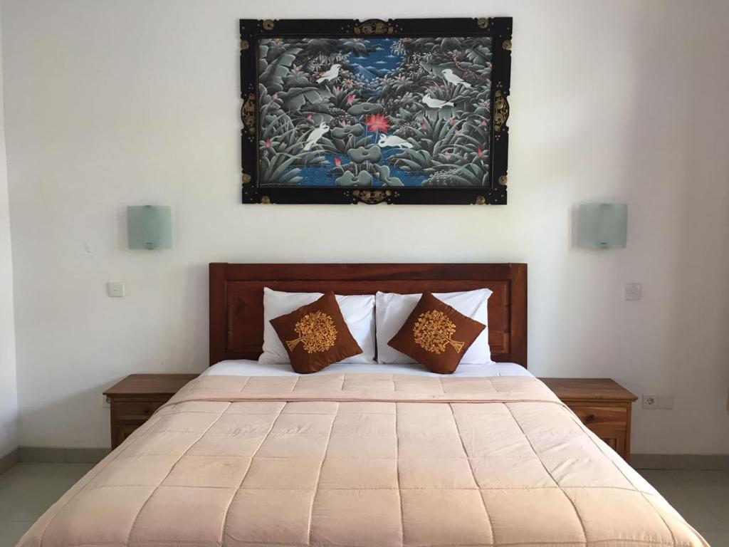 a bedroom with a bed with a painting on the wall at Agus Tri Homestay in Sanur