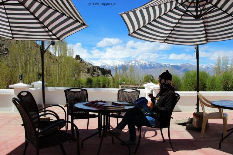 a woman sitting at a table under two umbrellas at Smanla guest house in Leh