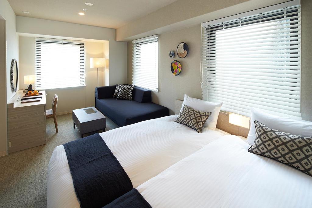 a bedroom with a bed and a chair and a couch at DEL style Osaka Higashi Temma by Daiwa Roynet Hotel in Osaka