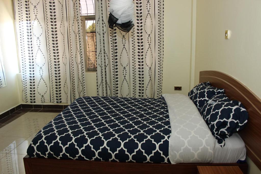 a bedroom with a bed and a window with curtains at Gees Inn in Nakuru