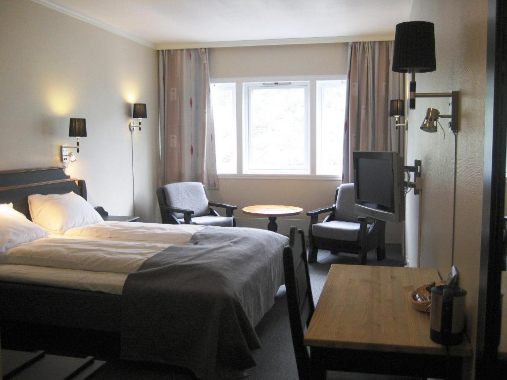 a hotel room with a bed and a table and a tv at Motell Nor-Kro in Bromma