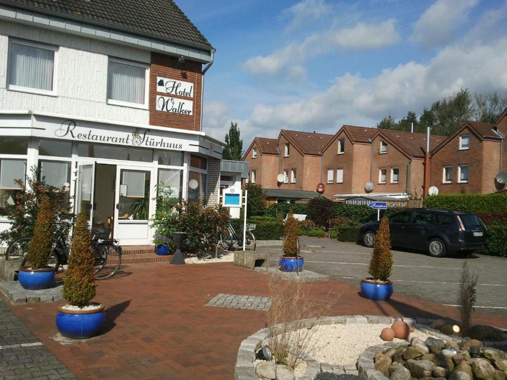 ein Parkplatz mit Topfpflanzen vor einem Gebäude in der Unterkunft WH Monteurhotel Papenburg Nord in Papenburg