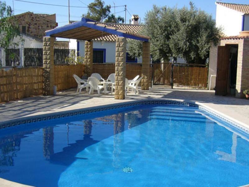 Casa Rural La Noria في La Escucha: مسبح في حديقة خلفية مع شرفة