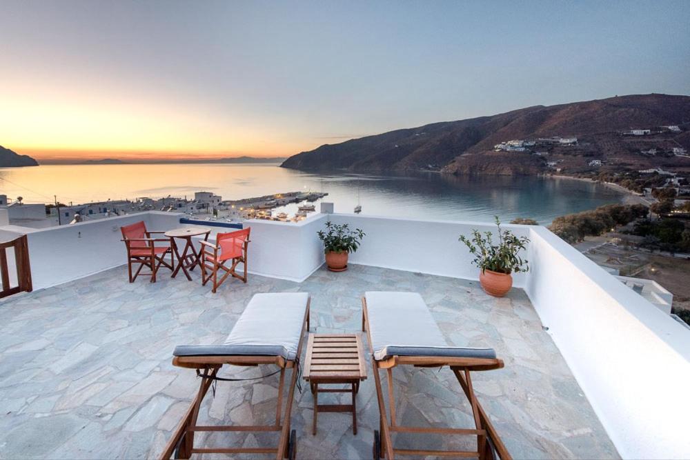 een balkon met tafels en stoelen en uitzicht op de oceaan bij Erisimo in Aiyiáli