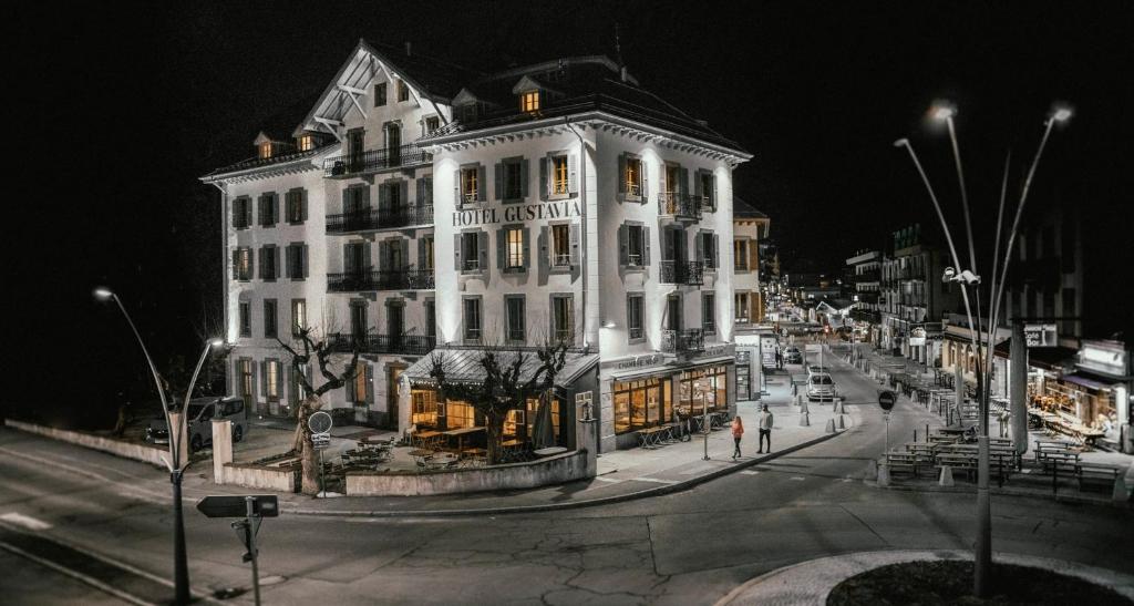 a large white building on a city street at night at Langley Hotel Gustavia in Chamonix