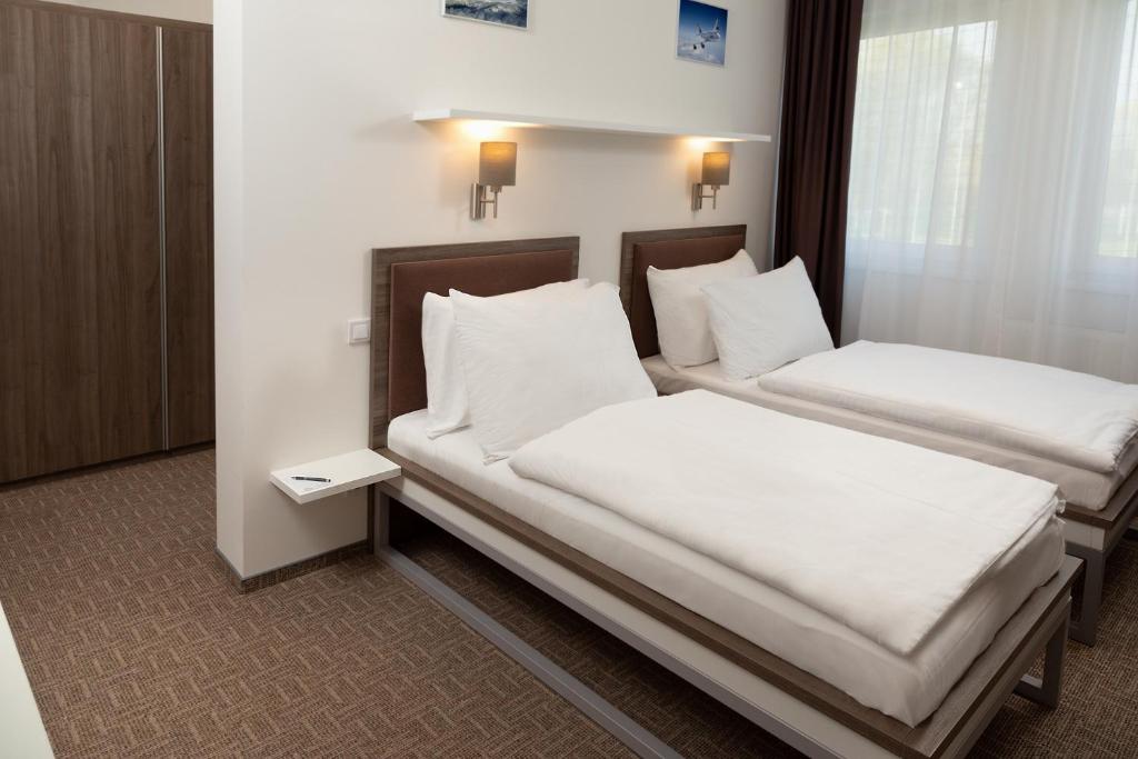 dwa łóżka w pokoju z białymi prześcieradłami i poduszkami w obiekcie Skyhotel Prague w Pradze