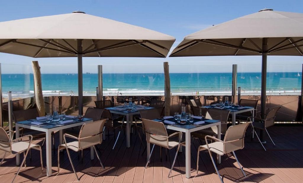 a restaurant with tables and umbrellas on the beach at Grand Hôtel Des Thermes in Saint Malo