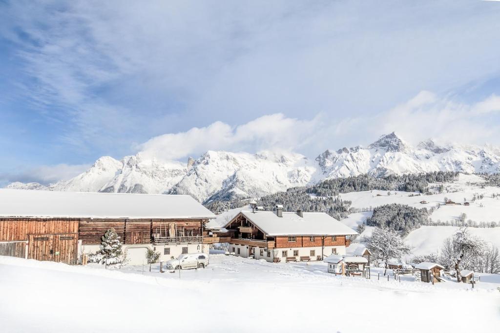 a lodge in the snow with mountains in the background at Christernhof in Maria Alm am Steinernen Meer