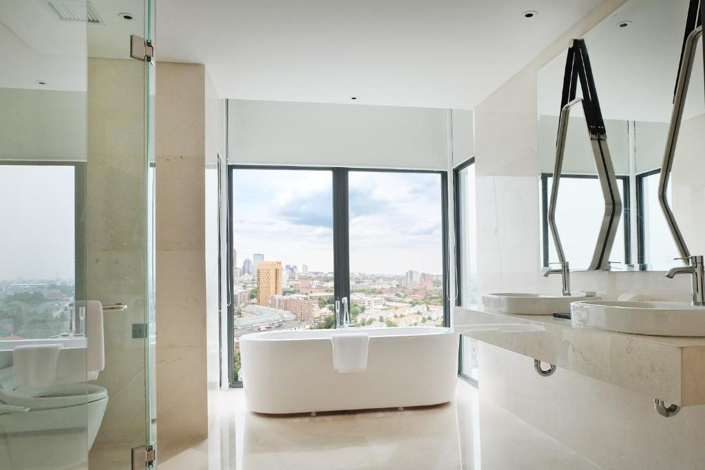 a white bathroom with two sinks and a window at Goodrich Suites, Jakarta in Jakarta