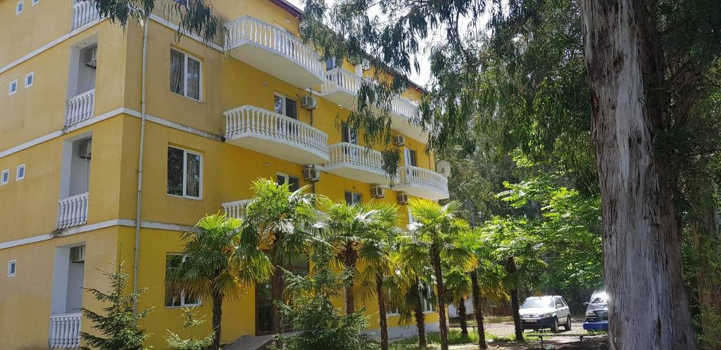 a yellow building with palm trees in front of it at Ureki - Evkalipt in Ureki