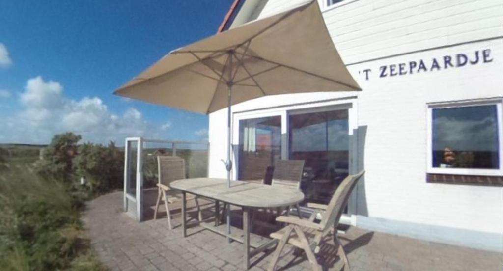 een tafel en stoelen met een parasol op een patio bij 't Zeepaardje in Midsland aan Zee