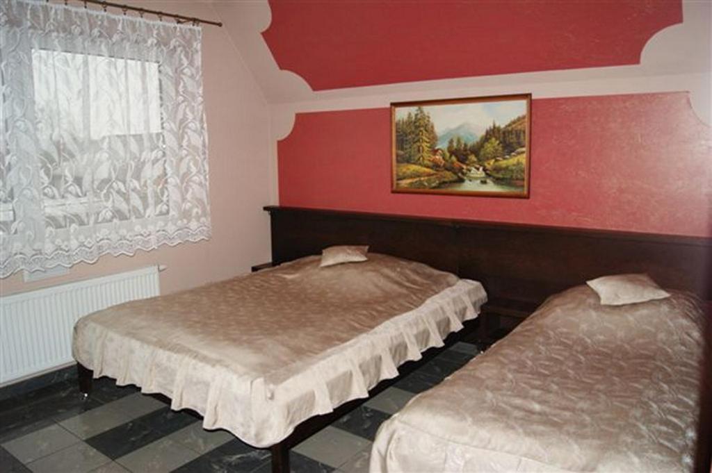 2 camas en una habitación con paredes rojas en Pokoje Gościnne Gum-Bar, en Biskupice