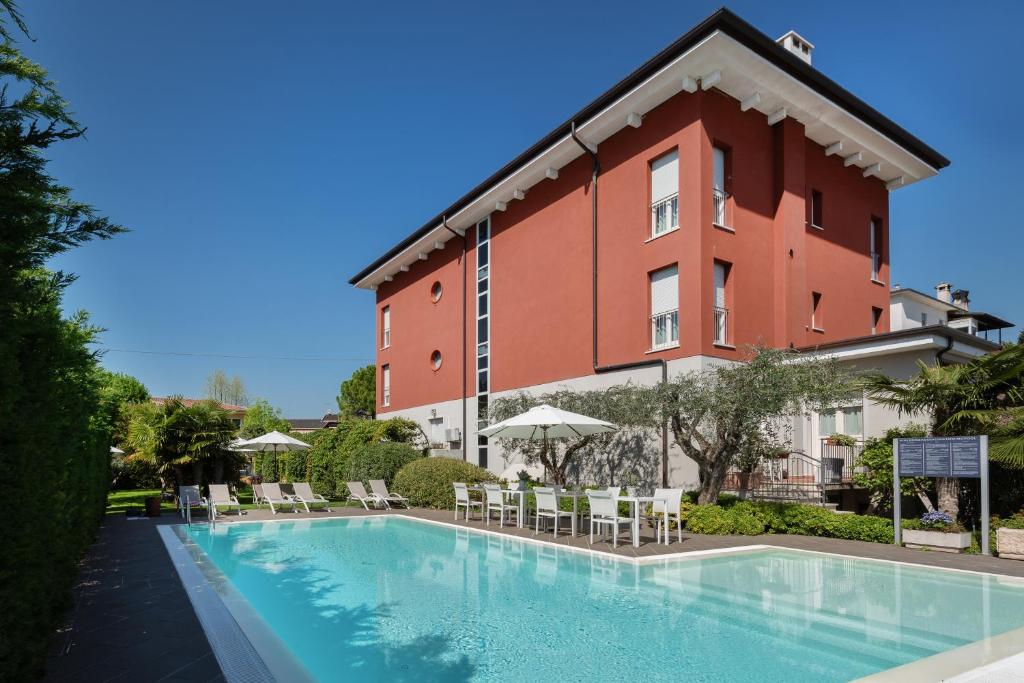 a hotel with a swimming pool in front of a building at Vialeromadodici Rooms & Apartments in Lazise