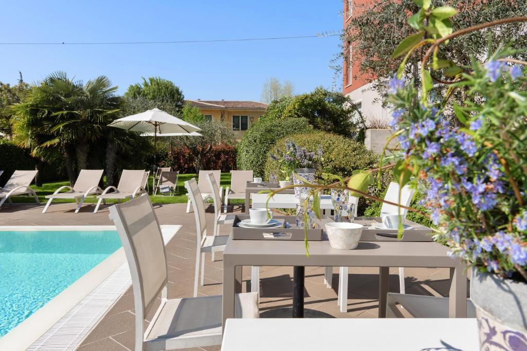 a patio with a table and chairs next to a pool at Vialeromadodici Rooms & Apartments in Lazise