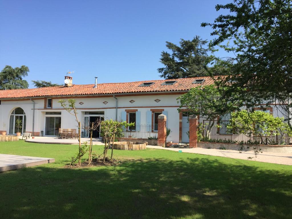 una gran casa blanca con un jardín delante de ella en La Garoffe, en Pibrac