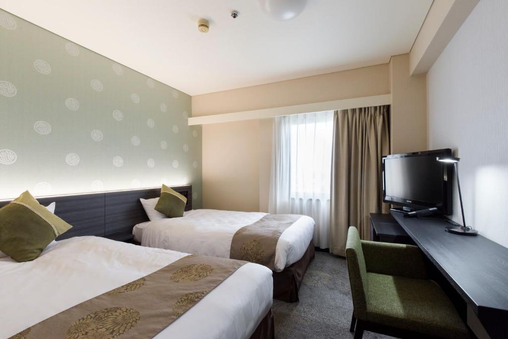 a hotel room with two beds and a flat screen tv at Takamatsu Tokyu REI Hotel in Takamatsu