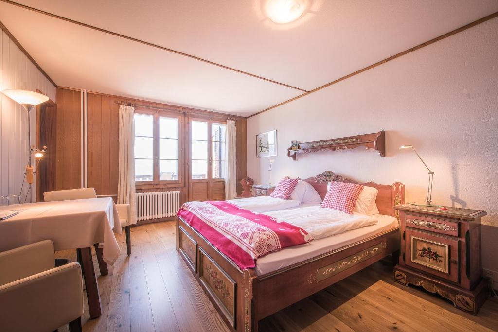 a bedroom with a bed and a table and a window at Hotel Fassbind Beausite in Beatenberg