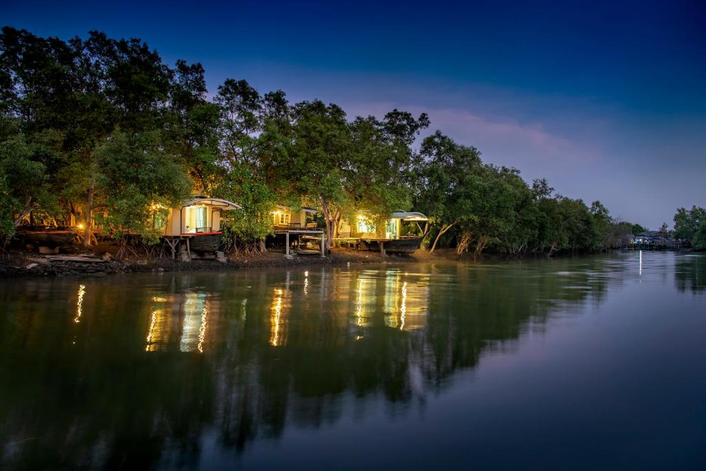 a house on the shore of a river at night at รตะธารา รีสอร์ท ratathara resort in Ban Khlong Tamru