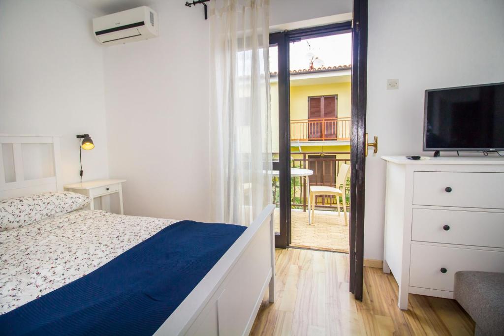 a bedroom with a bed and a television and a balcony at Pineta House Vidos in Poreč