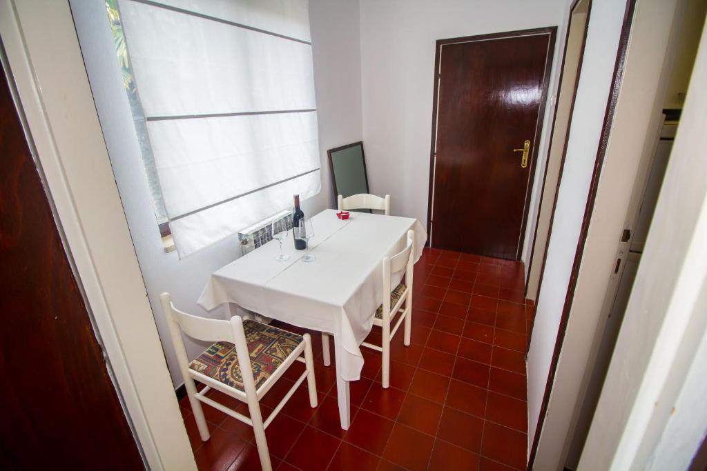 a white table and chairs in a room with a window at Pineta House Vidos in Poreč