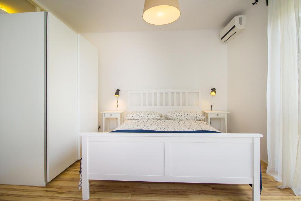 a white bedroom with a white bed in a room at Pineta House Vidos in Poreč