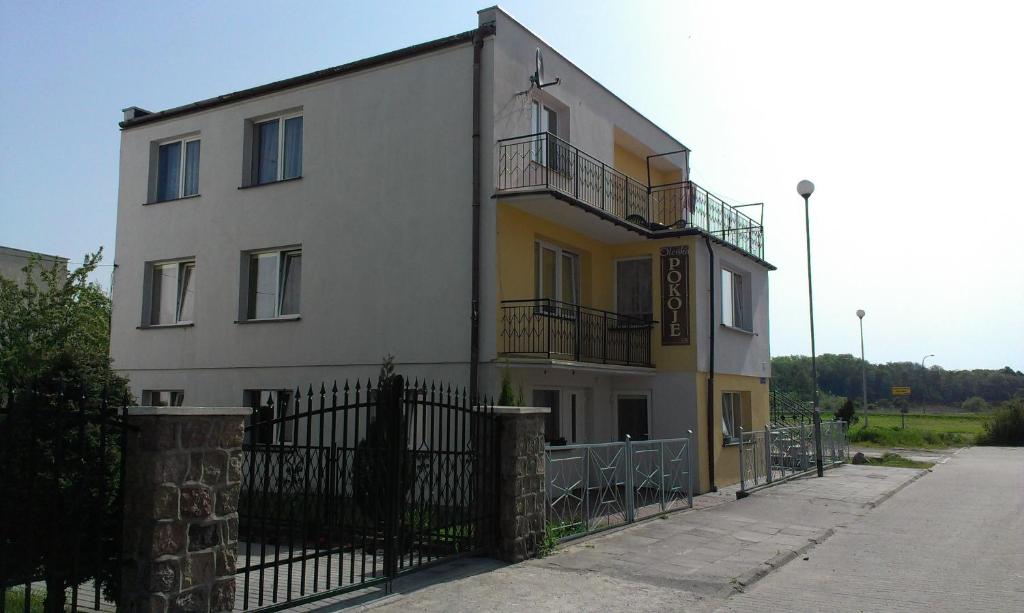 a white and yellow building with a black fence at OLEŃKA in Darlowko