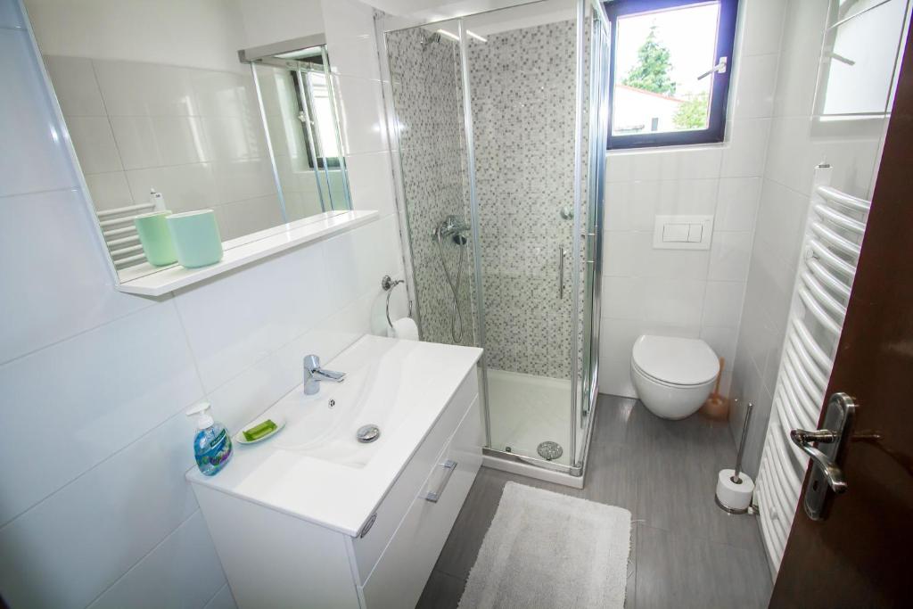 a white bathroom with a shower and a sink at Pineta House Vidos in Poreč