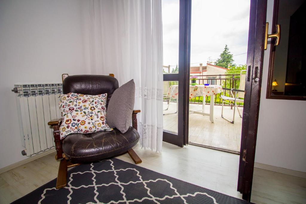 a leather chair with a pillow on a balcony at Pineta House Vidos in Poreč