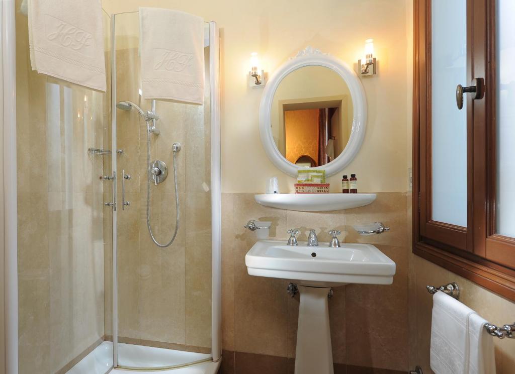 a bathroom with a sink and a shower and a mirror at Hotel Flora in Venice