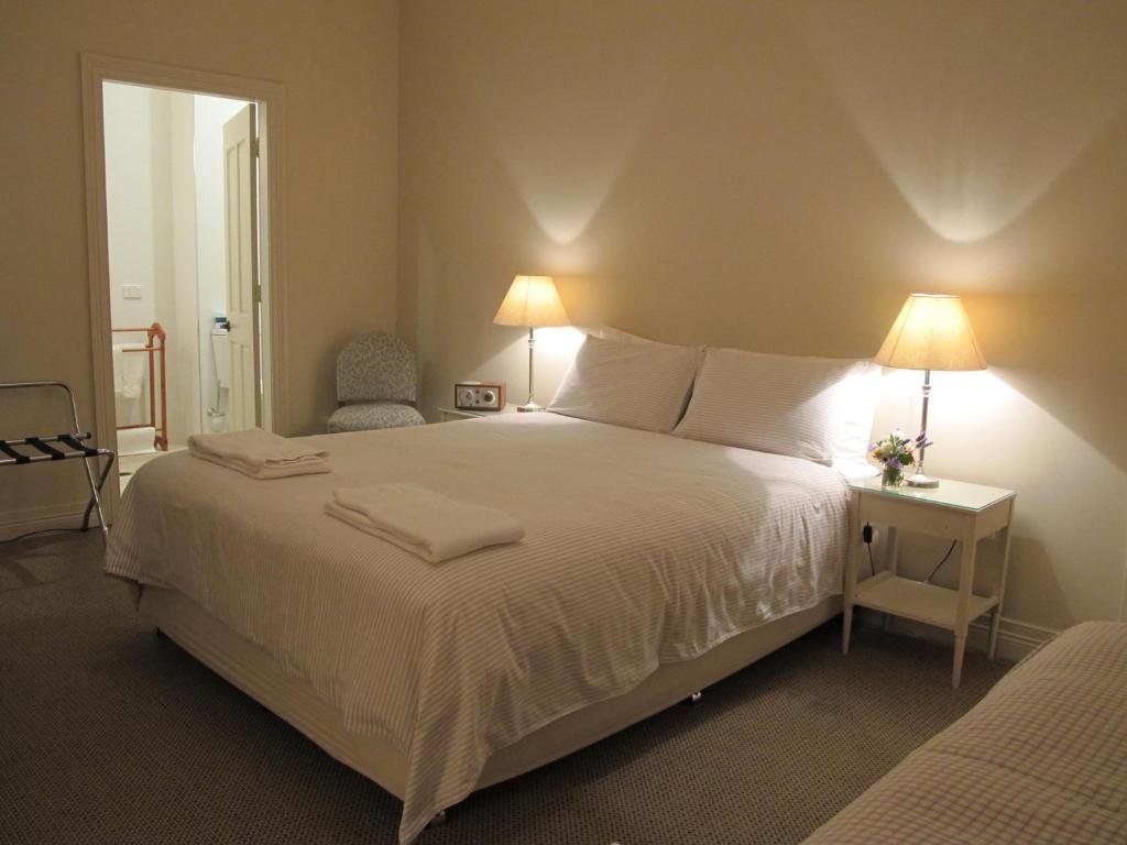 a bedroom with a large white bed with two lamps at The Playhouse Hotel in Barraba