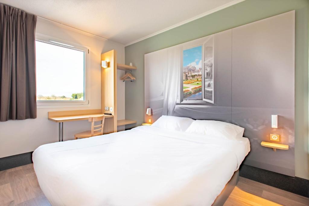 Un dormitorio con una gran cama blanca y una ventana en B&B HOTEL Vannes Ouest Golfe du Morbihan, en Vannes